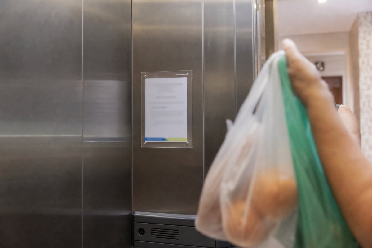Aviso impresso em moldura de acrílico dentro do elevador de um prédio residencial